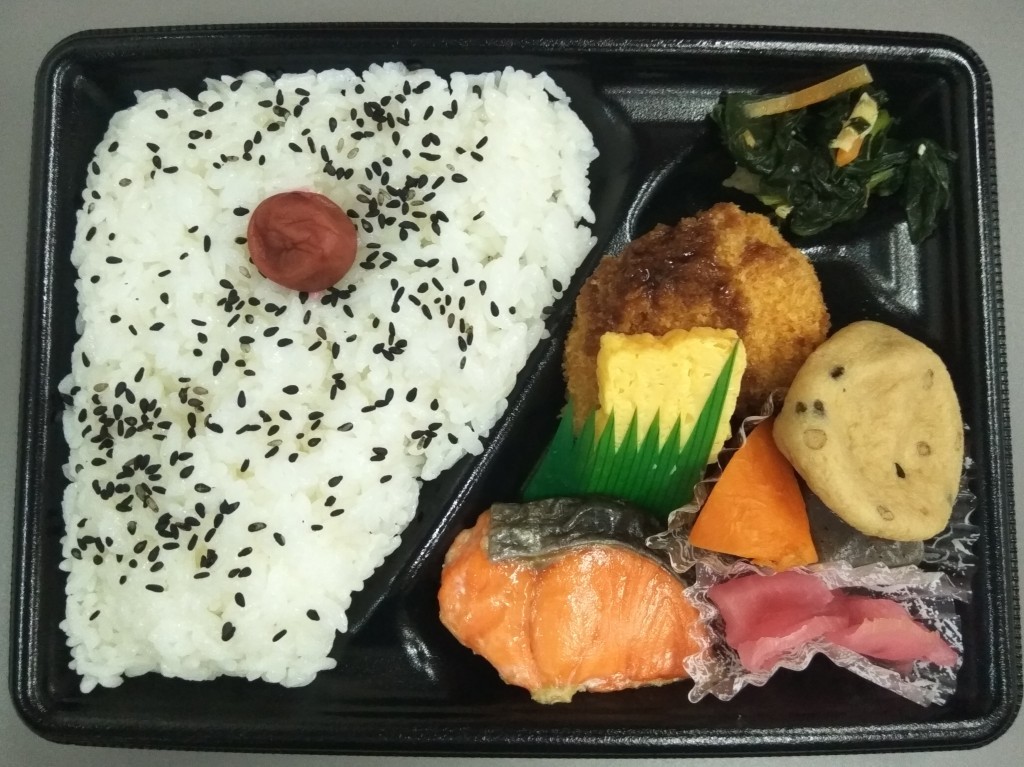 A lunch box with rice decorated with umeboshi. A lunch box with rice decorated with umeboshi.